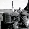 Alexander Oro in the driver's seat on his farm tractor near Stettler, Alberta in the 1950s.