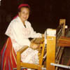 Rita Matiisen is proudly wearing a traditional Estonian costume while weaving at her loom.
